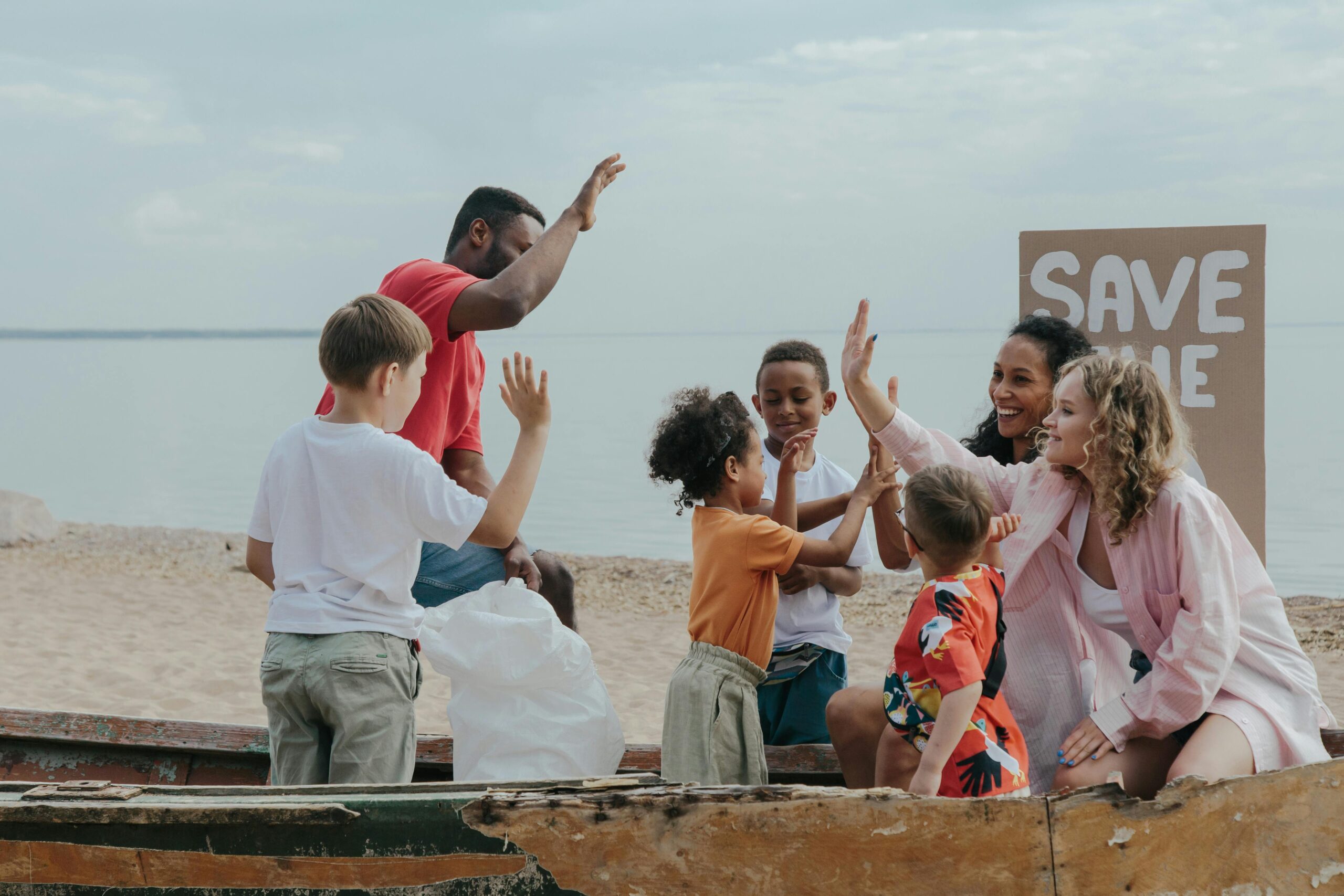 A diverse group of people enjoying a beach cleanup, promoting 'Save the Planet'.
